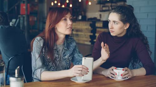 Two people talking warmly over coffee at a café table